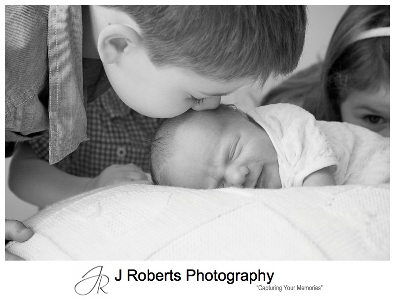 Smiling newborn as big brother kisses his head - newborn baby portrait photography sydney